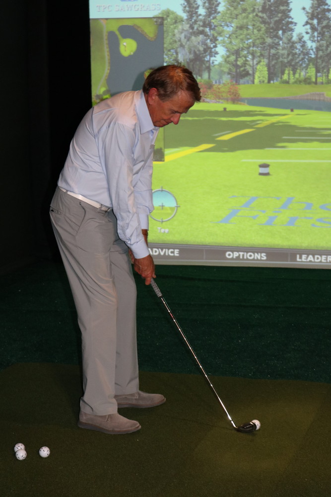 Former PGA Tour Commissioner Tim Finchem prepares to take a swing at The First Tee Experience’s golf simulator.